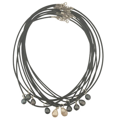 A set of multi-strand black cord necklaces with small irregular dark beads and a few pale pinkish-beige beads, arranged on a white surface.